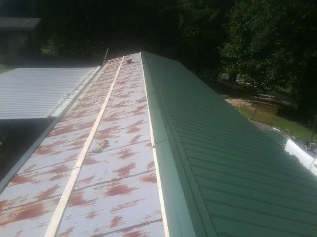 Old rusted panels beside newly installed green metal roofing — Wind Damage Roof Repair by Roofing Brothers in Mardela Springs