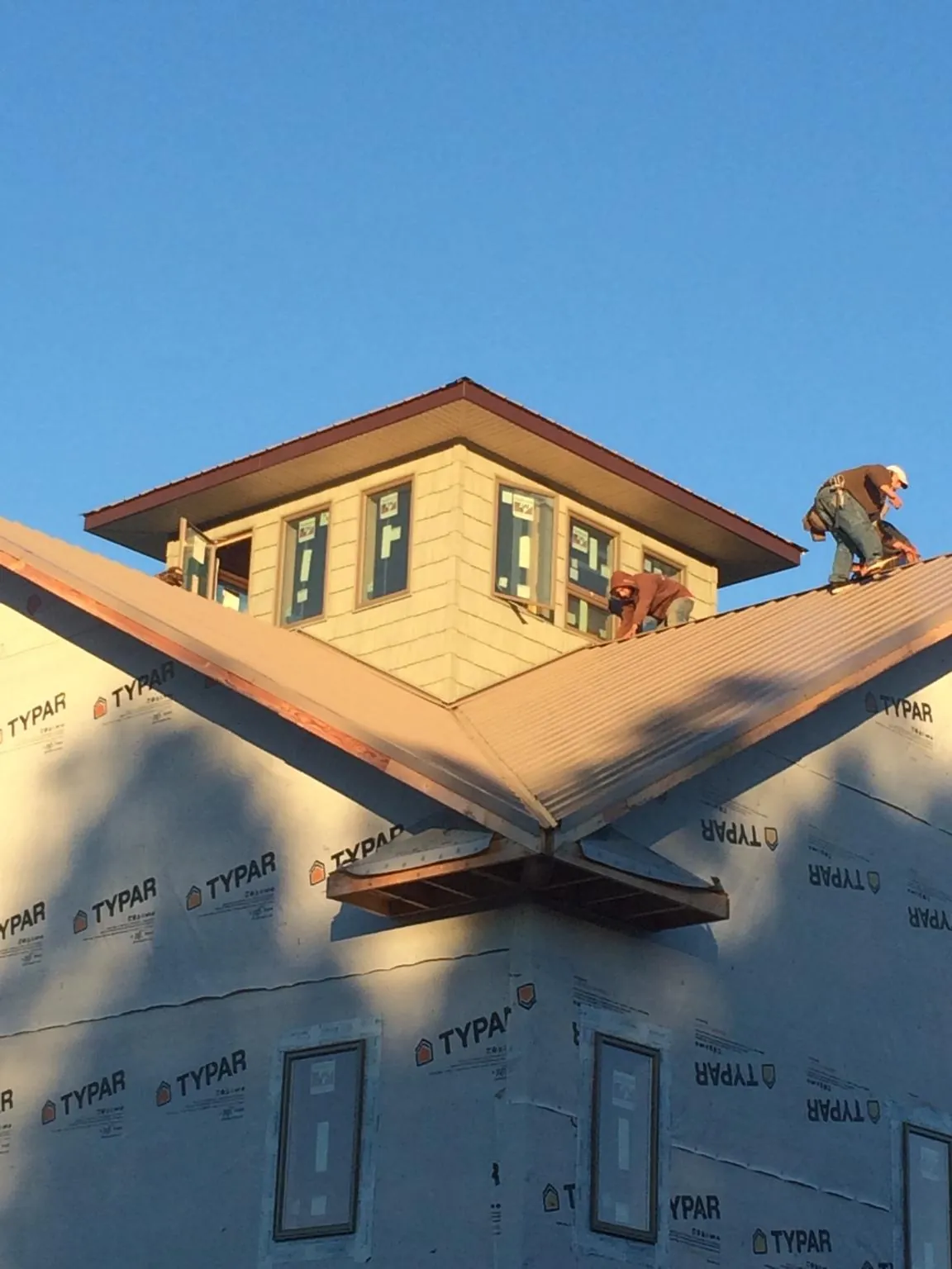 Roofers working around a rooftop cupola on a new metal roof at sunset — Roof Waterproofing in Mardela Springs by Roofing Brothers